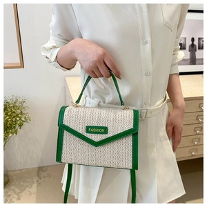 Détail du sac en paille tressée avec garniture en cuir vert et logo Fashion en métal