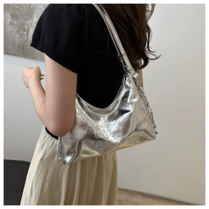 Close-up of metallic silver tote bag with embossed lettering and metal chain detail