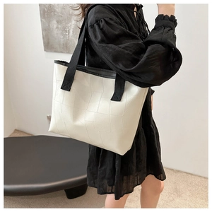 Detail view of the geometric quilted tote bag featuring black contrast trim and woven strap