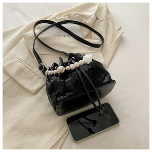 Detail of black drawstring bucket bag with pearl and metal ball decorative chain strap
