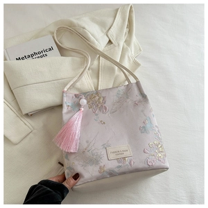 Gros plan du sac en satin rose avec broderie florale et de longues franges élégantes