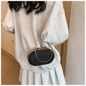 Detail of black glitter evening bag with gold bow clasp and metallic chain strap