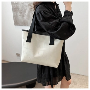 Detail of geometric embossed white leather tote bag with contrasting black textile straps