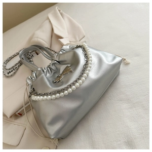 Close-up of silver pleated handbag with butterfly hardware and pearl chain detail