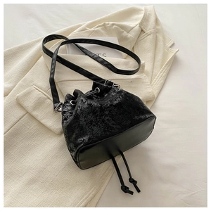 Detail of black drawstring bucket bag with retro textured finish on beige blazer