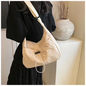 Detail of minimalist cream nylon crossbody bag with adjustable strap on model