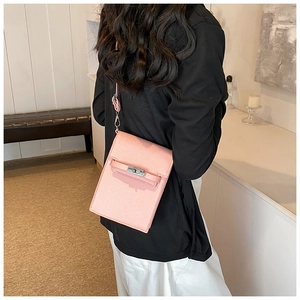 Detail of pink leather mini square crossbody bag showing the metal twist lock and slim strap