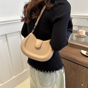 Beige faux leather half-moon shoulder bag styled with casual denim in a retro interior