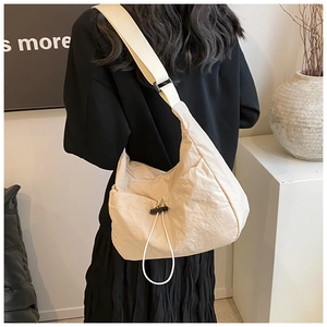 Back view of model wearing a minimalist beige pleated crossbody bag with black drawstring