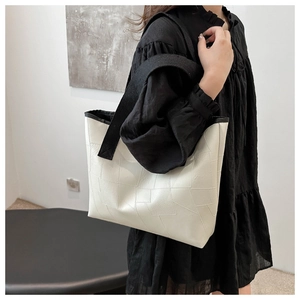 Close-up of white tote bag featuring geometric stitching and contrasting black straps