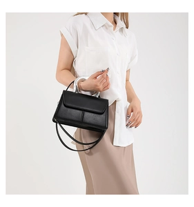 Détail du sac bandoulière minimaliste en cuir noir avec poignée en métal argenté