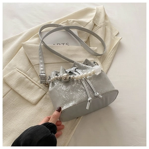 Close-up of silver cracked leather bucket bag with decorative pearl beaded handle