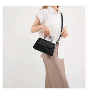 Détail d'un sac à main en cuir noir avec une poignée métallique argentée unique