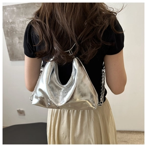 Détail du sac hobo argenté avec lettres embossées et bandoulière en chaîne métal