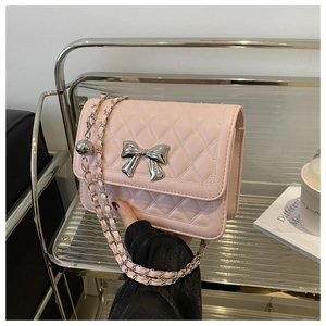 Detailed view of pink quilted handbag with silver metal bow and chain shoulder strap