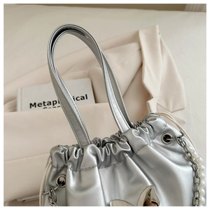 Detail of silver metallic drawstring bucket bag with pearl strap and chain links