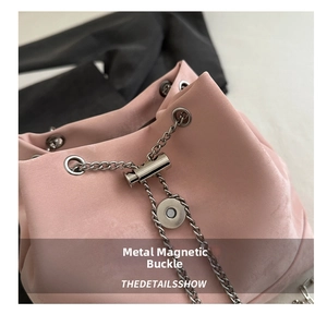 Detail of pink suede bucket bag featuring silver magnetic snap closure and metal chain