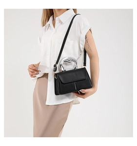 Détail du sac à bandoulière noir avec une poignée en métal argenté et une bandoulière