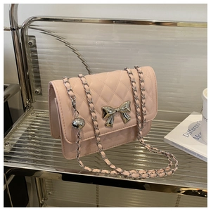 Detail of pink quilted crossbody bag featuring a silver bow buckle and chain strap
