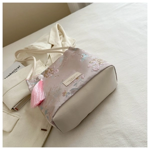 Détail de broderies florales sur sac seau en soie avec long gland rose