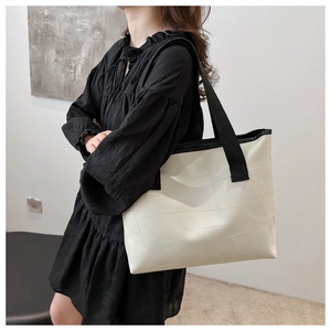 Detail view of large white PU leather tote bag with geometric paneling and black straps