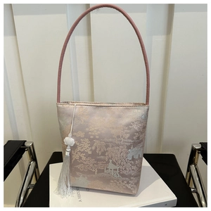 Détail du sac seau en satin de soie avec jacquard floral et pompon décoratif