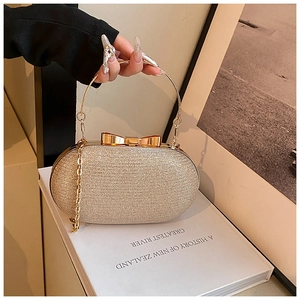 Detail of gold oval evening clutch bag with sequins, bow clasp and round metal handle