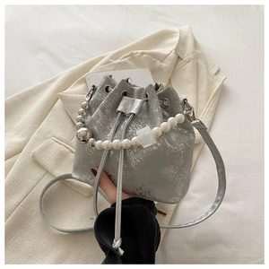 Close-up of silver bucket bag with pearl beaded handle and cracked metallic texture