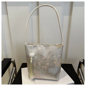 Détail du sac seau chinois avec broderie florale et pendentif à pompon blanc décoratif