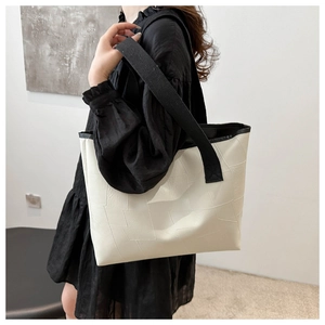 Detail of cream tote bag with black wide strap and geometric patchwork stitching