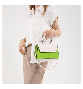 Detail of green crossbody bag with silver abstract handle and cream white flap cover