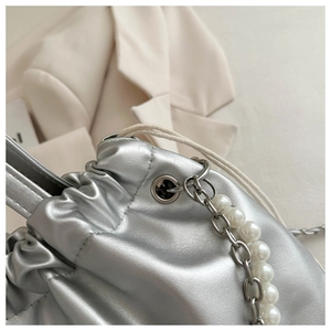 Detail of silver metallic drawstring bucket bag with pearl chain strap and leather texture