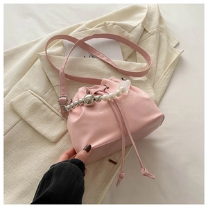 Pink drawstring bucket bag with pearl and silver bead handle on a white blazer