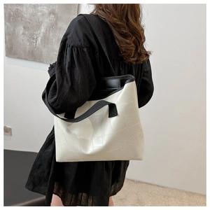 Detail view of the white geometric patchwork tote bag shown on a model shoulder