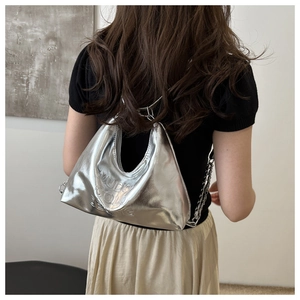 Detail of silver metallic crescent bag featuring embossed MUDO text and chain strap