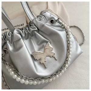 Detail of silver metallic bucket bag with butterfly hardware and pearl chain strap