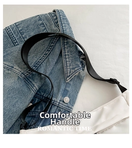 Détail du sac bandoulière en nylon blanc avec sangle noire sur veste en jean