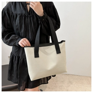 Detail of minimalist cream tote bag with black trim and geometric patchwork texture