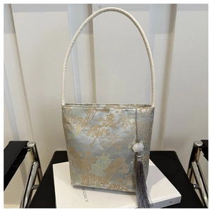Détails de broderies dorées avec pavillons et pins sur le sac en satin argenté