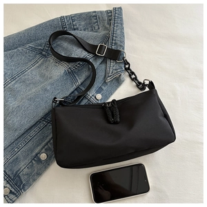 Detail of black nylon crossbody bag with chunky chain strap and dual zipper knots