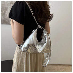 Close-up of metallic silver hobo bag featuring embossed textures and metal chain detail