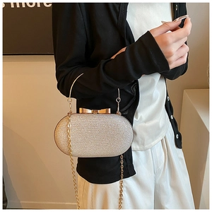 Close-up of elegant silver sequin clutch with gold butterfly clasp and chain strap