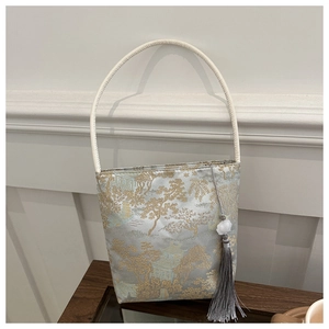 Détail du sac seau en satin jacquard bleu et doré aux motifs de paysages traditionnels