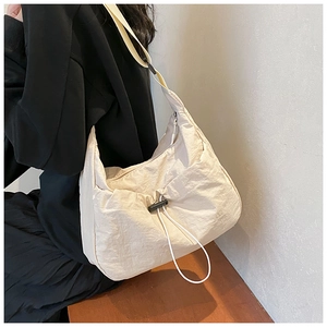 Detail of beige nylon crossbody bag showing drawstring detail and moon crescent shape