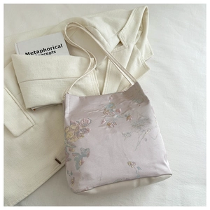 Gros plan sur la broderie florale d'un sac fourre-tout rose aux fines bretelles