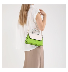 Détail du mini sac vert contrasté avec poignée coeur en métal et bandoulière blanche