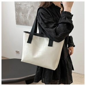 Minimalist white leather tote bag with black straps worn on shoulder for daily style