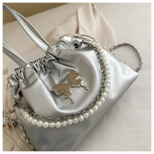 Detail of silver metallic drawstring bucket bag with butterfly emblem and pearl chain strap