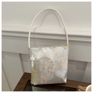 Vue détaillée des motifs floraux jacquard et du gland décoratif d'un sac seau beige