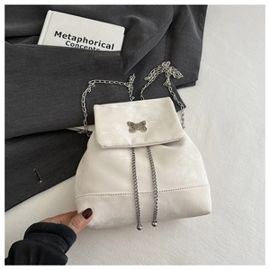 Close-up of stylish off-white backpack featuring silver butterfly ornament and chain detail